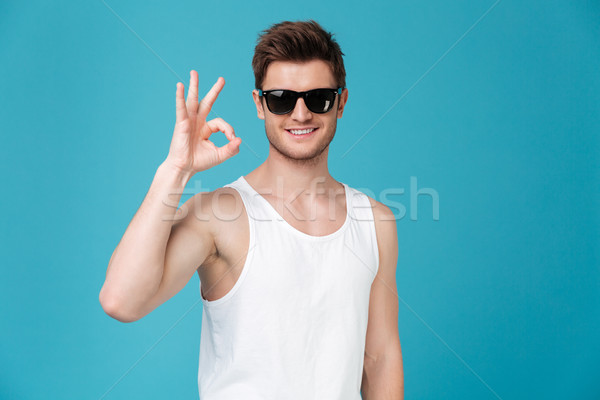 Happy young guy in sunglasses showing okay gesture Stock photo © deandrobot
