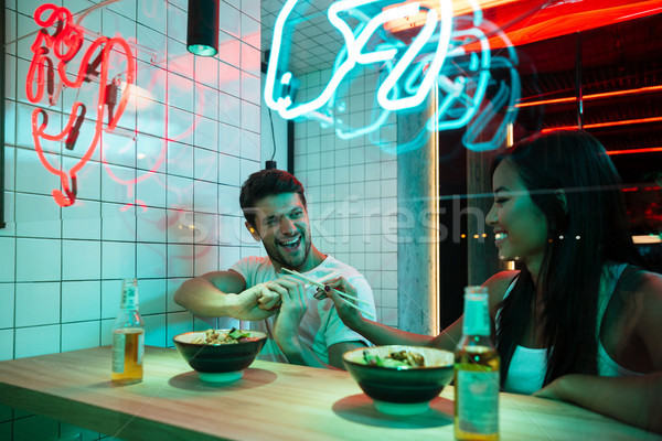 Multiethnic smiling loving couple sitting in cafe eating. Stock photo © deandrobot