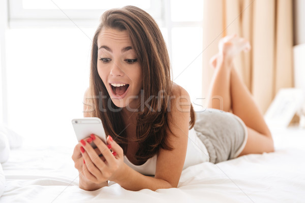 Close up portrait of happy excited woman using mobile phone Stock photo © deandrobot