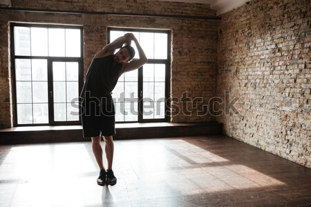 Stock photo: Young confident sportsman warming up at the gym