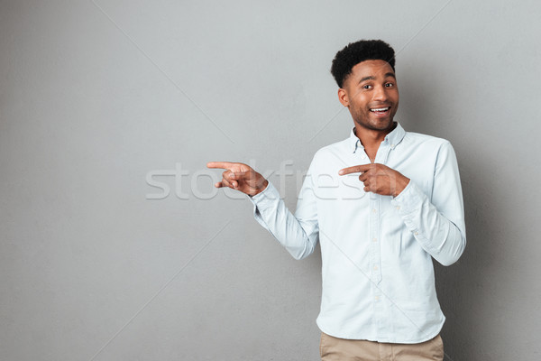 Stock photo: Smiling excited african man pointing finger away