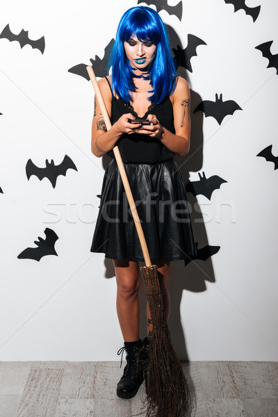 Angry young womand with broom chatting by phone. Stock photo © deandrobot
