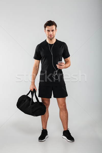 Handsome cheerful young sports man using phone listening music Stock photo © deandrobot