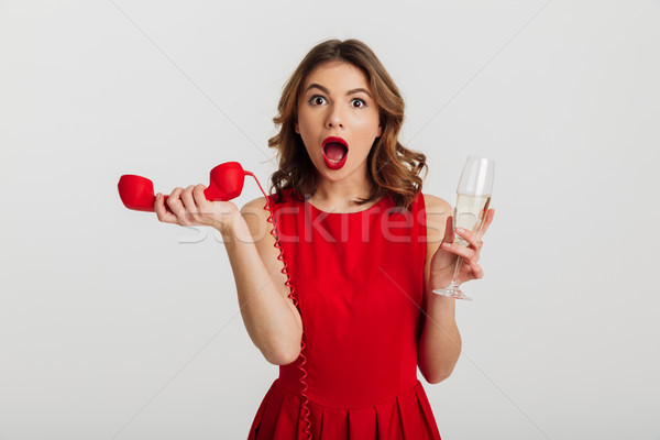 Portrait étonné jeune femme robe rouge téléphone [[stock_photo]] © deandrobot