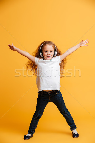 Happy girl dancing isolated over yellow Stock photo © deandrobot