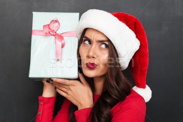 Intrigued brunette woman in red blouse and christmas hat Stock photo © deandrobot