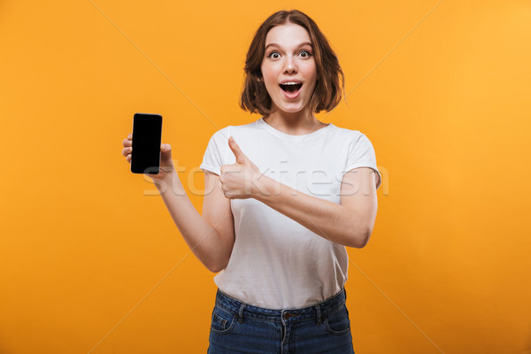 Excited young woman showing display of by mobile phone. Stock photo © deandrobot