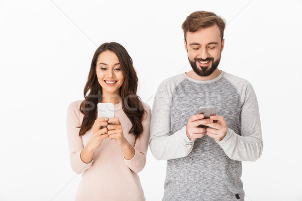 Happy young loving couple chatting by mobile phones. Stock photo © deandrobot