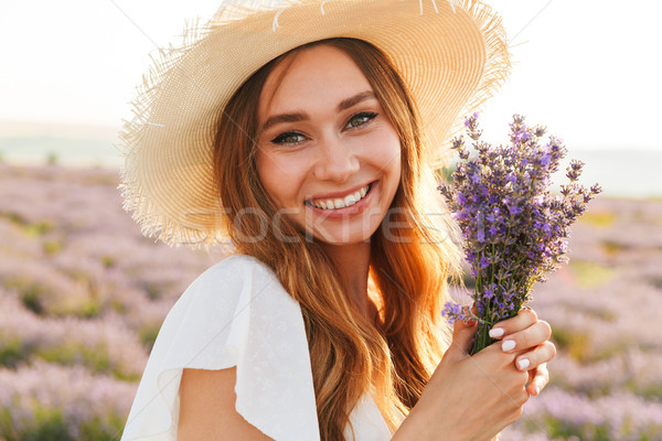 Beautiful young girl in straw hat holding lavender bouquet Stock photo © deandrobot