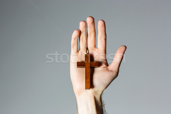 Male hand holding wooden cross on gray background Stock photo © deandrobot