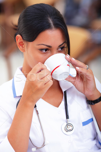 Young latin doctor having a break and drinking coffee Stock photo © deandrobot