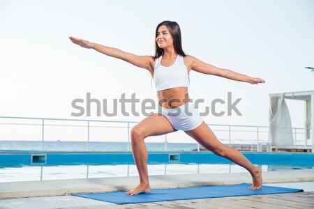 Woman doing stretching exercises on yoga mat  Stock photo © deandrobot