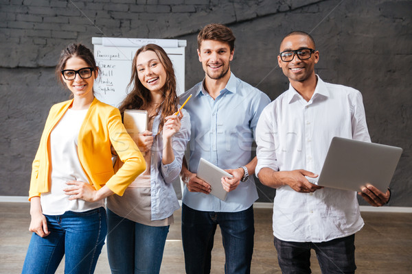 Group of cheerful business people with tablet and laptop Stock photo © deandrobot