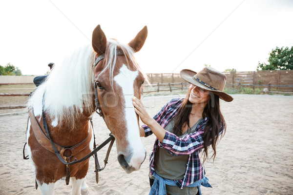 Smiling woman cowgirl enjoying taking care of horse in village Stock photo © deandrobot