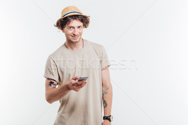 Stock photo: Smiling young man holding smart phone