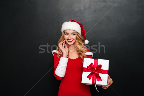 Cheerful young woman in santa claus costume holding gift box Stock photo © deandrobot