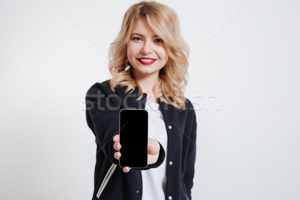 Beautiful young woman showing display of mobile phone. Stock photo © deandrobot