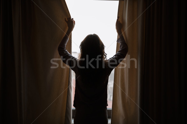 Siluetă femeie perdele vedere din spate fereastră negru Imagine de stoc © deandrobot