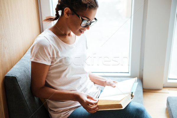 African woman sitting in library and reading books. Stock photo © deandrobot