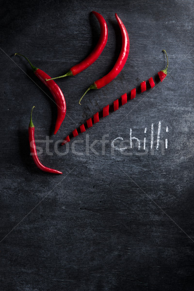 Photo of cut chilli pepper over dark background. Stock photo © deandrobot