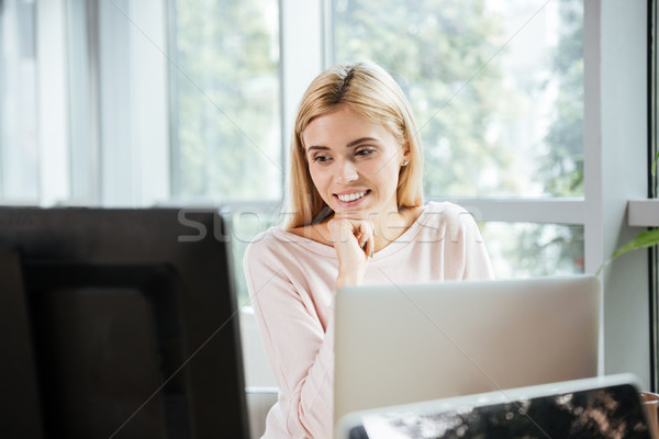 Cheerful lady sitting in office coworking using computer. Stock photo © deandrobot