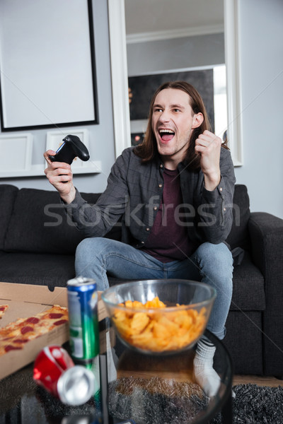 Happy man gamer sitting at home and play games Stock photo © deandrobot