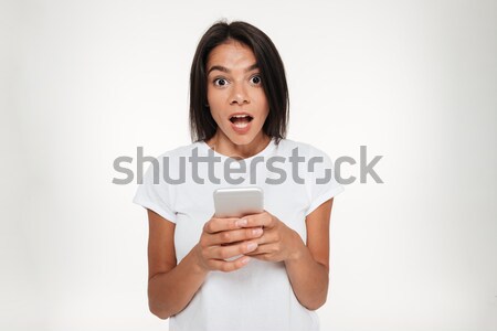 Portrait of a shocked bunette woman holding mobile phone Stock photo © deandrobot