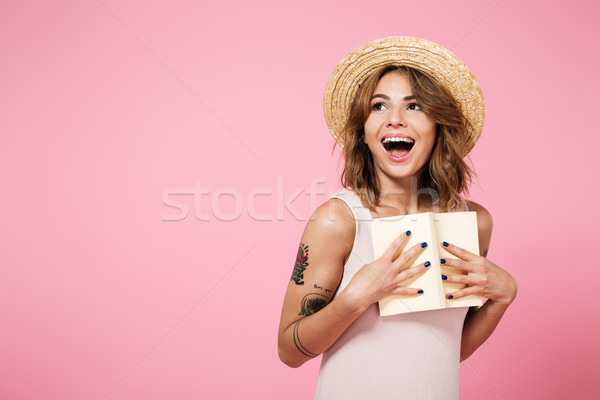 Portrait of a positive girl in summer hat holding book Stock photo © deandrobot