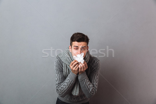 Displeased illness man wearing warm scarf holding napkin. Stock photo © deandrobot