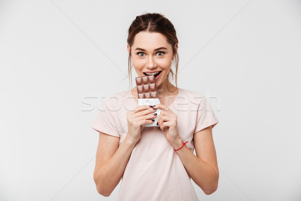 Portrait of a smiling pretty girl eating chocolate bar Stock photo © deandrobot
