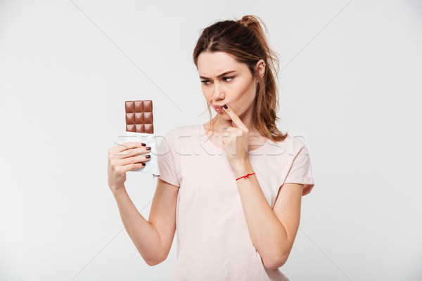 Stock photo: Portrait of a thoughtful pretty girl holding chocolate bar