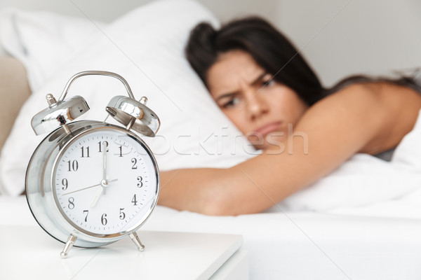 Image of frustrated woman 20s lying in bed on pillow, and lookin Stock photo © deandrobot