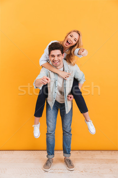 Full length photo of smiling couple having fun and pointing fing Stock photo © deandrobot