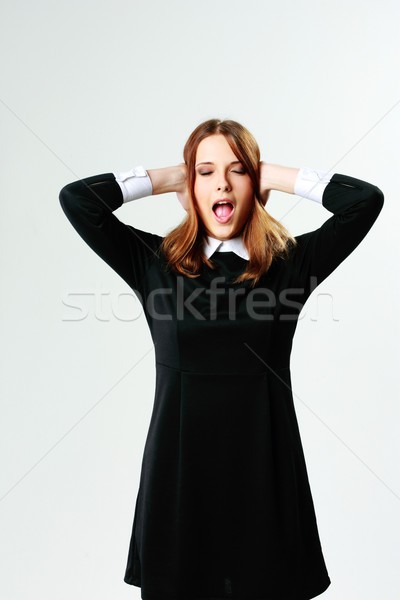 Young woman closing her ears and screaming on gray background Stock photo © deandrobot