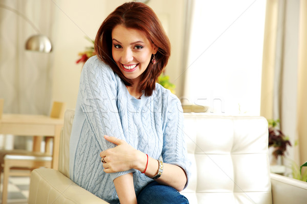 Smiling woman sitting on the sofa at home Stock photo © deandrobot