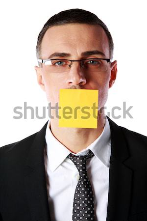 Portrait of businessman with mouth covered with a paper card over white background Stock photo © deandrobot