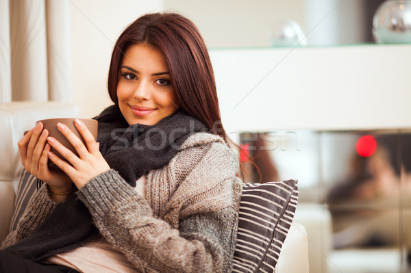 Happy young woman sitting on sofa in cosy cloths with cup of coffee Stock photo © deandrobot