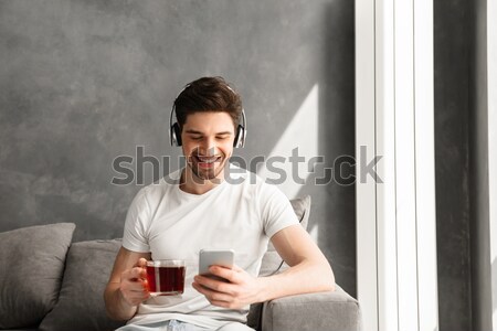 Cheerful business man sitting at the table with cup of coffee Stock photo © deandrobot