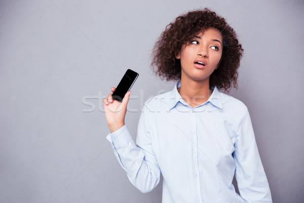 Bored afro american woman holding smartphone Stock photo © deandrobot