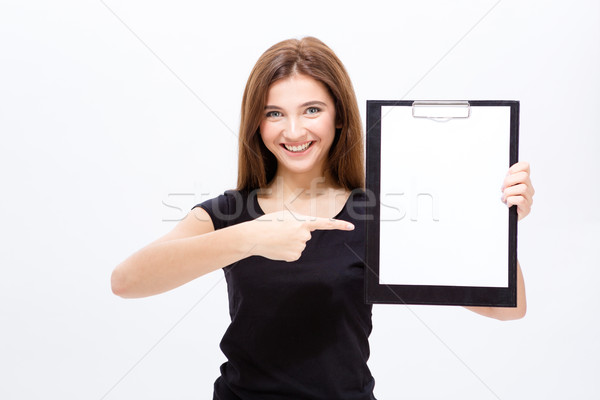 Cheerful attractive young woman showing clipboard and pointing on it Stock photo © deandrobot
