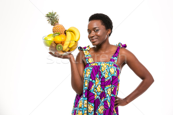 Cheerful attractive african american  woman holding glass bowl with fruits Stock photo © deandrobot