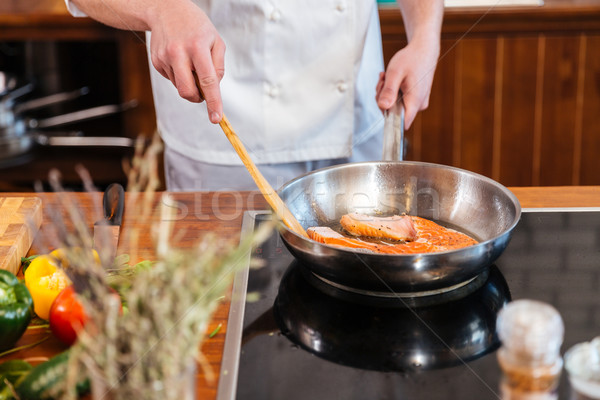 Hands of chef making fresh salmon steak on frying pan  Stock photo © deandrobot