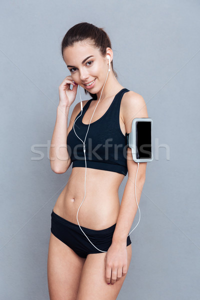 Smiling young woman with smartphone and earphones Stock photo © deandrobot