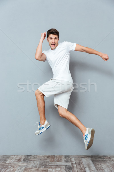 Funny man jumping over gray background Stock photo © deandrobot