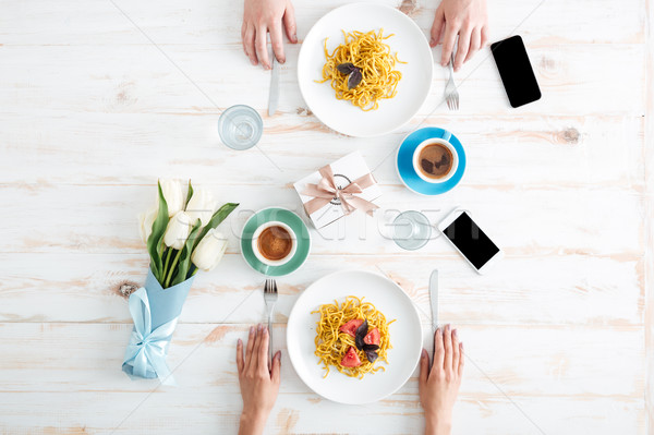 Hands of couple eating pasta and drinking coffee on table Stock photo © deandrobot