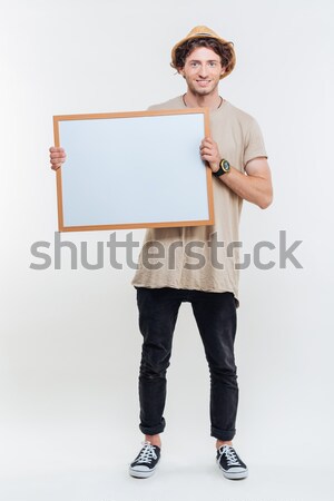Full length of young man walking and holding blank whiteboard Stock photo © deandrobot
