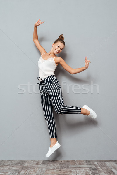 Full length portrait of a cheerful cute woman jumping Stock photo © deandrobot