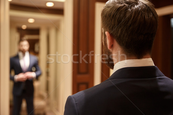 Man looking in mirror wearing suit Stock photo © deandrobot