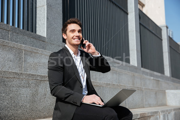 Alegre homem sessão telefone laptop sorrir Foto stock © deandrobot