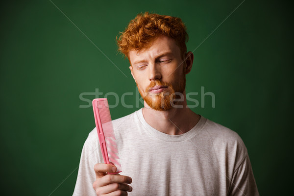 Young readhead beardy man looking at pink comb Stock photo © deandrobot